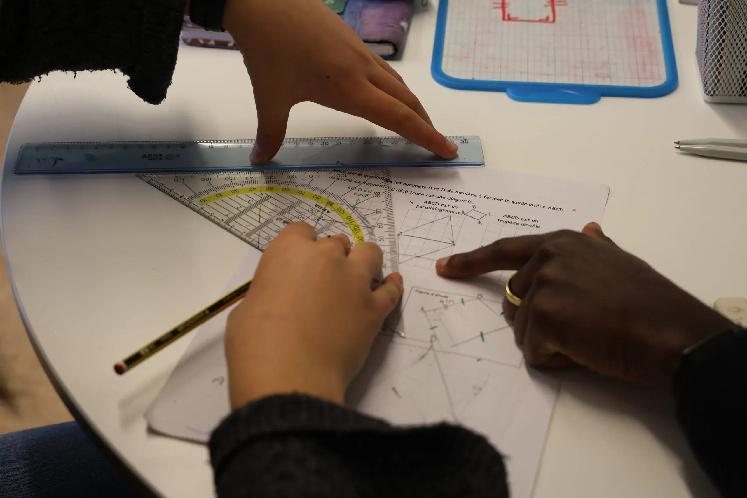 Étudiants travaillant sur des plans et des outils de géométrie en classe.